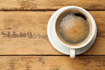 Cup of aromatic coffee on wooden table, top view. Space for text
