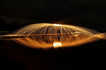 Long exposure of burning steel wool in the dark, on the surface of water