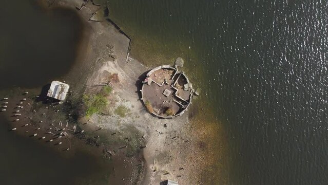Ascending drone footage over an artificial island with vegetation and boats around in the sea