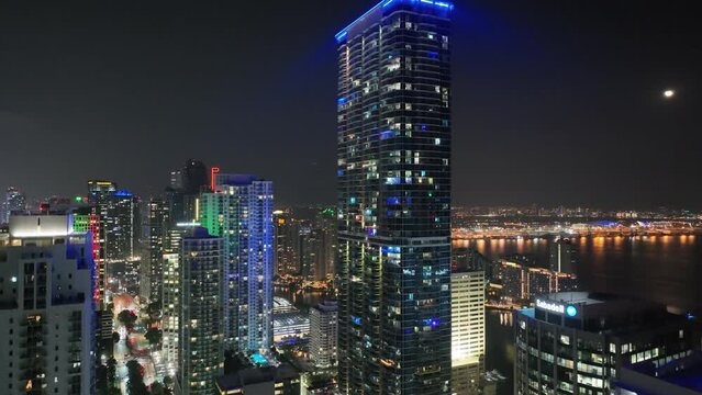 Aerial footage of Miami downtown towers with shiny water in the background at night