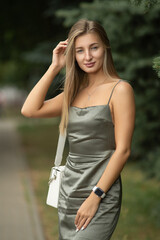 Portrait of a young beautiful blonde girl in a city summer park.