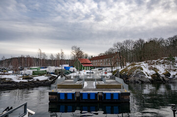 A wooden Norwegian cottage on the shore of the Oslo fjord on a winter day. Red Norwegian houses