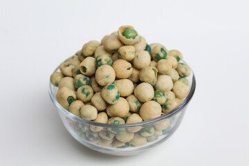 Fried green peas with dough flour, in transparent glass bowl, isolated on white background