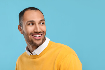 Smiling man with healthy clean teeth on light blue background. Space for text