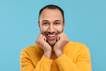 Portrait of smiling man with healthy clean teeth on light blue background