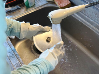 鍋の蓋を洗うゴム手袋をした手元