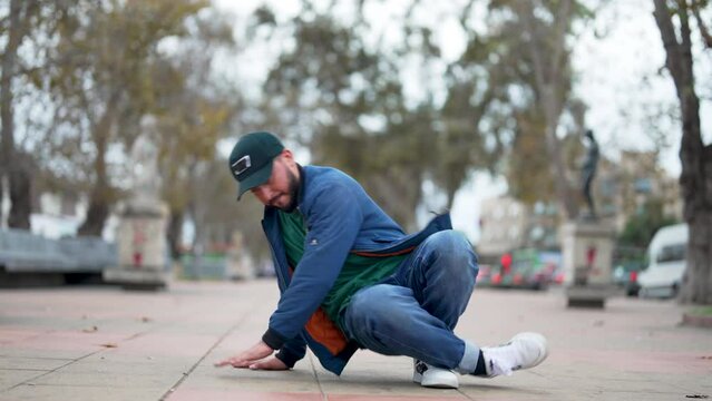 latin American breakdancer guy performing downrock or floor based footwork on the street