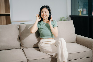 Naklejka premium Young asian woman relax on comfortable couch at home texting messaging on smartphone and tablet smiling girl use cellphone shopping online