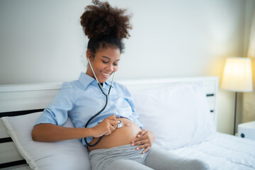 Young African American pregnant woman  Listen to her baby's voice with stethoscope with smile of...