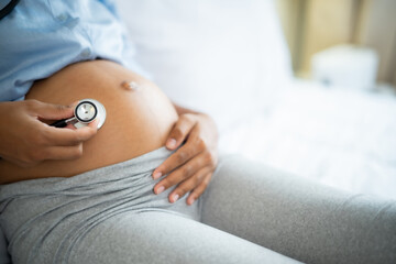 Crop of Young African American pregnant woman  Listen to her baby's voice with stethoscope with...