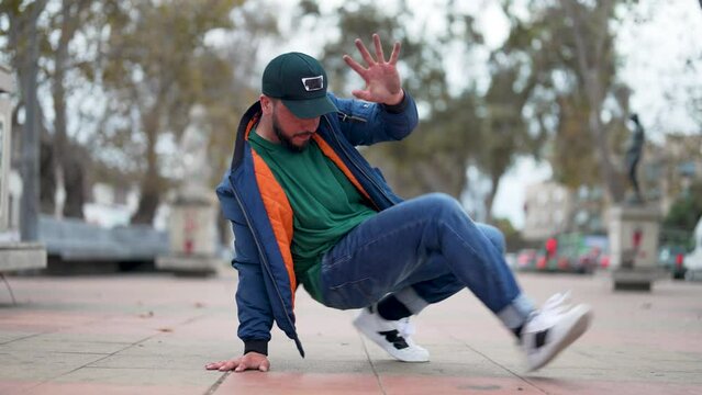 latin American breakdancer guy performing downrock or floor based footwork on the street