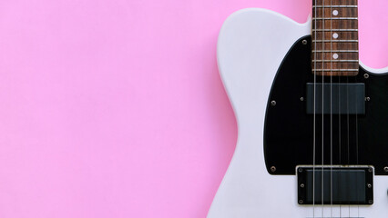 Fototapeta premium Black and white electric guitar on a pink background. Top view.