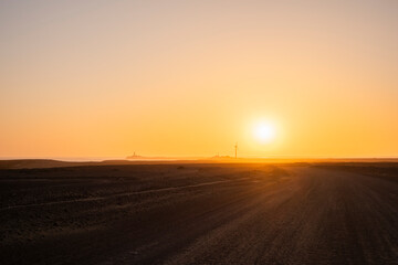 Carretera infinita de la arena con el sol de fondo a punto de esconderse por el horizonte