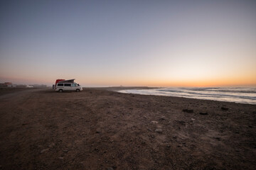 Coches aparcados en la arena en el atardecer 