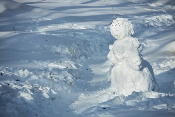 A snowman near the forest. The figure of a woman. Snow Sculpture