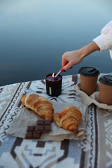 aesthetic photo. picnic on the pier with coffee and croissants, chocolate and candles