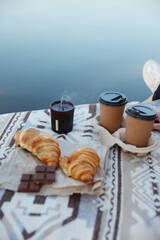aesthetic photo. picnic on the pier with coffee and croissants, chocolate and candles