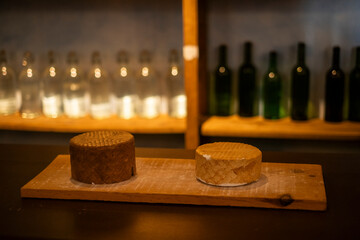 Maqueta de queso, estanterías de madera con botellas de vidrio