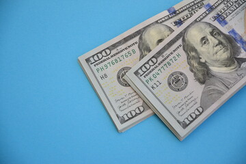 Bundles of one hundred dollar banknotes on blue background