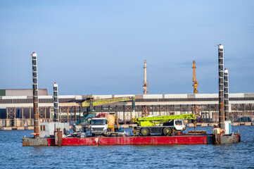 floating platform with crane for hydrotechnical works and concrete mixer trucks on deck