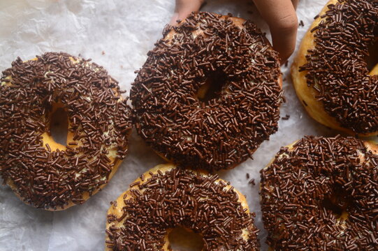 A hand is a holding Donuts with chocolate spinkle.  