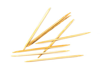 Many small toothpicks or wooden skewers lie disorganized on a white table