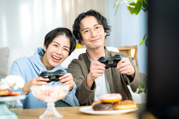 リビングでゲームをする若い日本人カップル