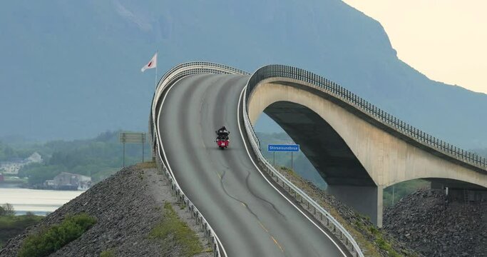 Couple rides a motorcycle on a winding Atlantic road in Norway.