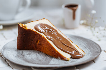 Popular Spanish cheesecake called San Sebastian cheesecake. It also known as burnt cheesecake. One piece of this dessert on white background with chocolate glaze on it.