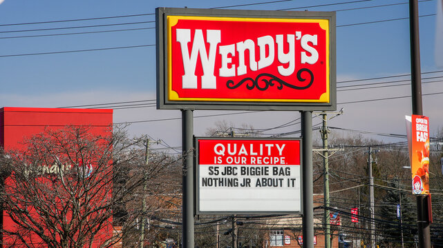 NORWALK, CT, USA - FEBRUARY 9, 2024:   Wendy's sign with building near Post road in Norwalk in nice sunny winter day