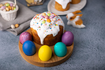 Easter kulich with candied fruits in white glaze with colorful sprinkles and painted eggs. Traditional Easter pastry. Easter holiday. Close-up, selective focus.