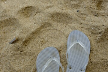 A pair of sandals on sands at beach. Women's flip flops. sandal jepit
