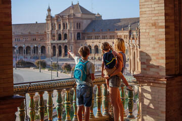 Tourists with kids admire famous square of Spain in Seville
