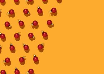Red Christmas baubles pattern on yellow background. Flat lay, top view, copy space. New Year greeting card mockup