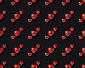 Pattern of red shiny hearts on black background. Valentine's Day card