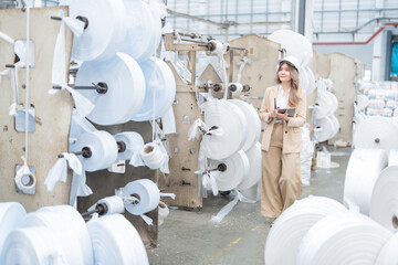 Inside a large plastic manufacturing factory, there are rolls of paper and Asian female engineers...