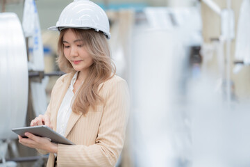 Closeup of half body female engineer Use a tablet to check the system. Wear a safety helmet and...