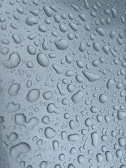 Small round dewdrops on the silver metal surface of the car