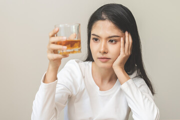 Alcoholism drunk, sad asian young woman hand holding glass of alcohol or whiskey, alone depressed female drink booze on background. Treatment of alcohol addiction, suffer abuse problem alcoholism.