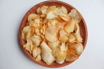 Cassava chips, in a wooden plate, isolated on white background, flat lay or top view