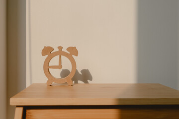Photo of wooden clock shape design, showing watch model shadow, putting on wood chair with sunlight in room.