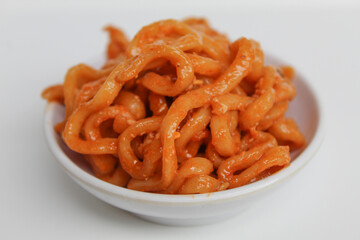 Spicy instant fried noodle in red color, in a small white bowl, isolated on white background