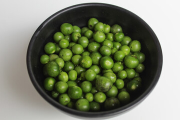 Fruit of Solanum nigrum, the European black nightshade or leunca, in a black bowl, isolated on white background, flat lay or top view