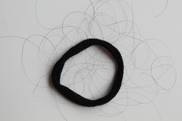 A black hair ties with strands of black hair. Hair loss or hair falling out or hair breakage