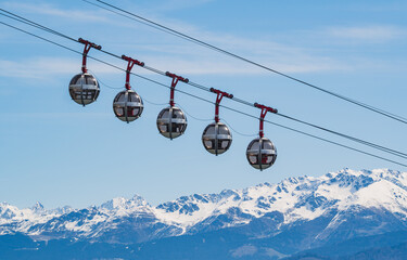 Gondola bubbles against the blue sky and the French Alps in the background. Cable car taking tourists to Fort de La Bastille in Grenoble, France - obrazy, fototapety, plakaty