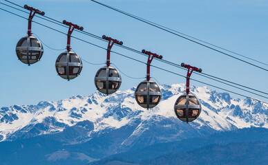 Gondola bubbles against the blue sky and the French Alps in the background. Cable car taking tourists to Fort de La Bastille in Grenoble, France - obrazy, fototapety, plakaty