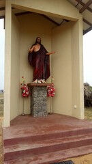 Close-up of a statue of Jesus, adorned with colorful flowers