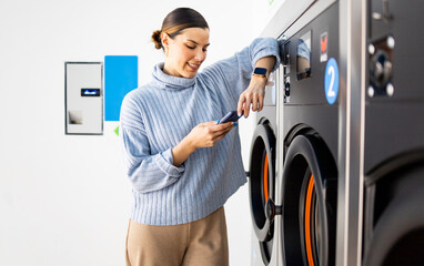 A pretty girl stands inside a self-service laundry. The woman waits to have her clothes washed...
