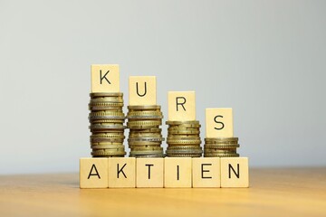 Aktienkurs und die Entwicklung von Investitionen, Kursen und Dividende an der Börse symbolisiert durch steigende und fallende Geldstapel und die Aufschrift Aktien Kurs