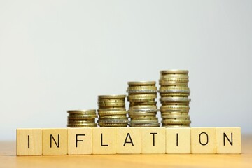 Stacked money coins and letters symbolizing the concept of inflation on white background